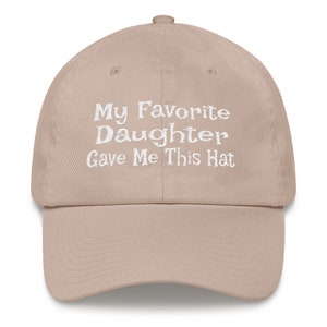 May include: A beige baseball cap with white embroidered text that reads "My Favourite Daughter Gave Me This Hat".
