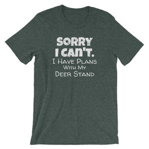 May include: A dark green t-shirt with the text "Sorry I can't. I have plans with my deer stand." printed in white.