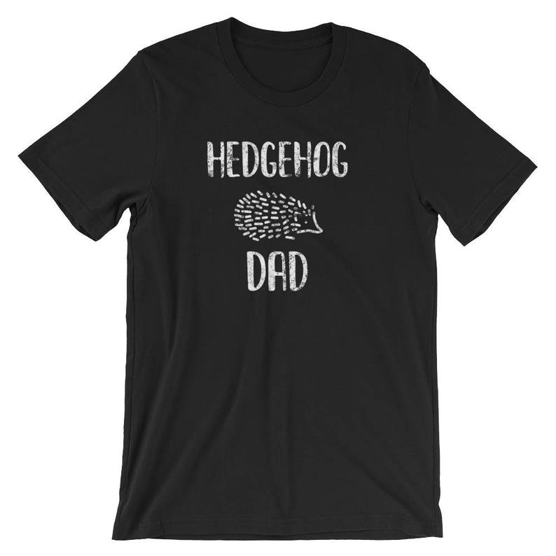May include: Black t-shirt with the words "HEDGEHOG DAD" in white, above a white illustration of a hedgehog. The shirt is a short-sleeved crew neck.