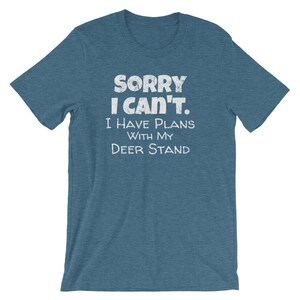 May include: A blue t-shirt with the text "Sorry I Can't. I Have Plans With My Deer Stand" in white.