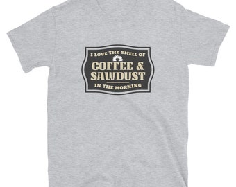 Op de afbeelding: Grijs T-shirt met een zwart-witte afbeelding met de tekst "Ik hou van de geur van koffie & zaagsel in de ochtend".