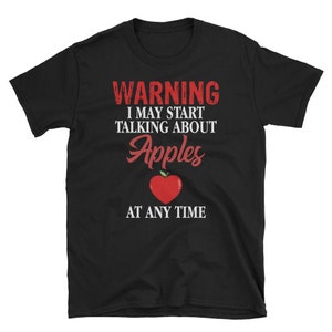 Puede incluir: Camiseta negra con texto blanco que dice "WARNING I MAY START TALKING ABOUT Apples AT ANY TIME". Una manzana roja con un tallo y una hoja verdes está en el centro del texto.