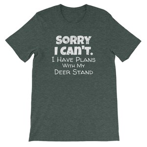 May include: A dark green t-shirt with the text "Sorry I can't. I have plans with my deer stand" in white.