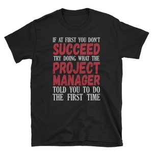 May include: Black t-shirt with white text that reads "If at first you don't succeed try doing what the project manager told you to do the first time."