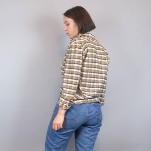 May include: A brown and white striped long-sleeved shirt with a collared neckline. The shirt is made of a soft, comfortable fabric and has a relaxed fit.