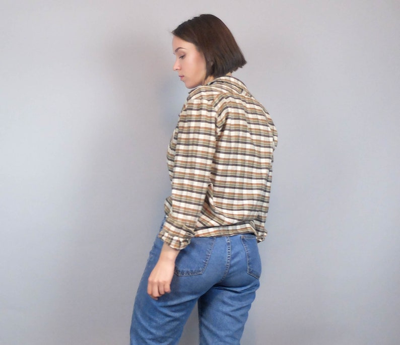 May include: A brown and white striped long-sleeved shirt with a collared neckline. The shirt is made of a soft, comfortable fabric and has a relaxed fit.