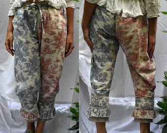 Op de afbeelding: Een crèmekleurige broek met een blauwe en rode bloemenprint. De broek heeft een geruite zoom en een trekkoord.