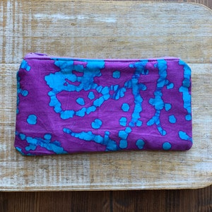 May include: A purple zippered pouch with a blue and white tie-dye pattern.