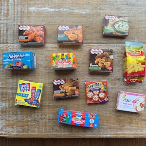 以下が含まれることがあります： 「チキンウィングス」、「ポテトスキンズ」、「ほうれん草とアーティチョーク」、「Fla-Vor-Ice」、「Otter Pops」、「Poppers」、「Icee」、「モッツァレラスティック」、「ベーグルバイツ」、および「itsu hoisin duck」を含む、ミニチュア食品箱のコレクション。