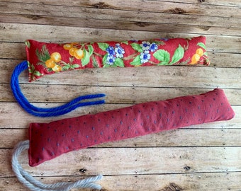 May include: Two cat toys, one with a red and white floral pattern and a blue cord, and the other with a red and white polka dot pattern and a gray cord.