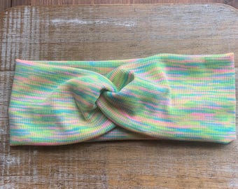 Puede incluir: Una diadema de color pastel con un diseño de nudo retorcido. La diadema presenta una textura acanalada y una mezcla de tonos verde claro, rosa, azul y amarillo. Este accesorio está diseñado para la comodidad y el estilo.