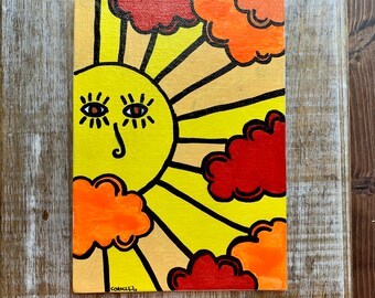 Puede incluir: Un lienzo pintado a mano con un sol amarillo con una cara sonriente y los ojos cerrados. El sol está rodeado de nubes naranjas y rojas sobre un fondo amarillo con rayos negros que emanan del sol.