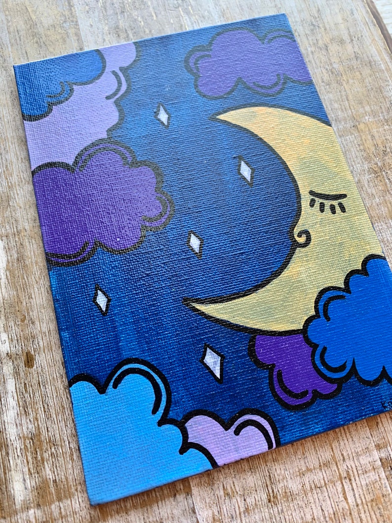 May include: A hand-painted canvas featuring a crescent moon with a closed eye and eyelashes, surrounded by purple, blue, and light blue clouds on a dark blue background. The moon is yellow with a white outline. The clouds have black outlines. There are white diamond-shaped stars scattered across the canvas.