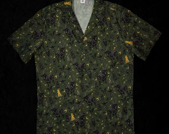 May include: Green button-up shirt featuring a repeating pattern of black cats, bats, moons, stars, and witch figures. The short-sleeved shirt has a V-neck collar and is made of a lightweight fabric.