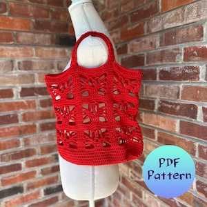 Può includere: Borsa a mano in crochet rosso con un motivo geometrico. La borsa ha un manico ed è esposta su un manichino bianco. Il testo "PDF Pattern" è su un cerchio blu.