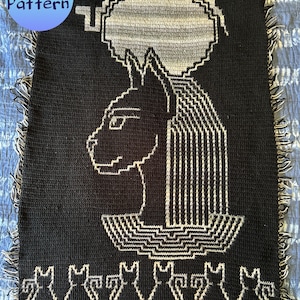 May include: Black and white crochet blanket featuring a stylized cat with a halo. The cat is surrounded by smaller cats at the bottom of the blanket.