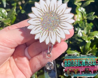 May include: White glitter sunflower badge reel with a clear plastic retractable badge holder.