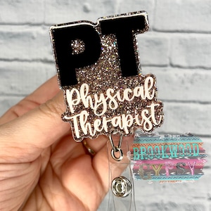May include: A gold glitter badge holder with a black "PT" and the text "Physical Therapist" in white. The badge holder is attached to a clear retractable badge reel.