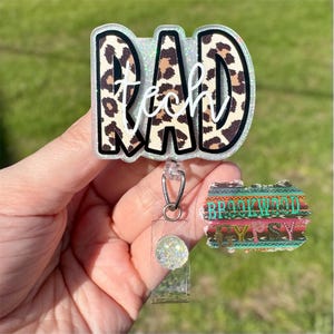 May include: A clear plastic badge holder with a leopard print design that says "Rad Tech" and a clear plastic retractable badge reel with a sparkly charm.