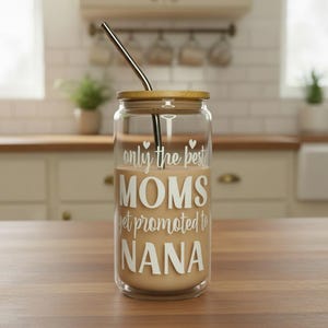 Puede incluir: Un vaso de vidrio transparente con tapa de bamb&uacute; y pajita de acero inoxidable. El vaso est&aacute; lleno de un l&iacute;quido marr&oacute;n claro y presenta el texto blanco "only the best MOMS get promoted to NANA".