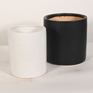 May include: Two ceramic planters, one white and one black. The black planter has a speckled brown glaze.