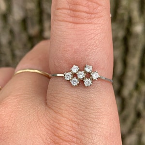 May include: A silver ring with a cluster of small, clear gemstones set in a delicate band.
