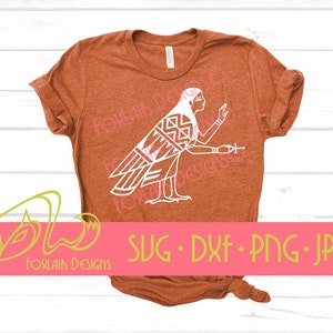 May include: A rust-colored t-shirt with a white graphic of a stylized bird with geometric patterns. The graphic is of a bird with wings spread and a human-like head. The text "SVG - DXF - PNG - JPG" is printed below the graphic.