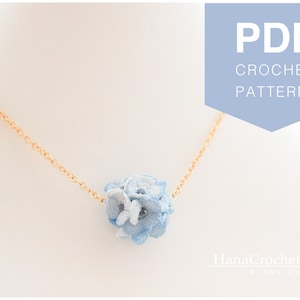 May include: A crochet pattern for a delicate necklace featuring a blue and white flower pendant. The pattern is available as a PDF download. The image shows the finished necklace on a white background.