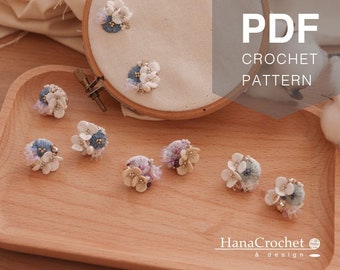 May include: A set of eight crocheted flower embellishments in shades of blue and white. The flowers are arranged on a wooden surface. The text "PDF CROCHET PATTERN" is visible in the upper right corner of the image.