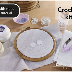 May include: Crochet kit with white and beige yarn, a wooden embroidery hoop with white fabric, white and iridescent sequins, and a small container of beads. The kit also includes a purple embroidery floss and a video tutorial.