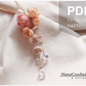 May include: PDF crochet pattern for a delicate necklace with a cascading design of crocheted flowers in shades of pink and white. The necklace features a gold chain and crystal accents.