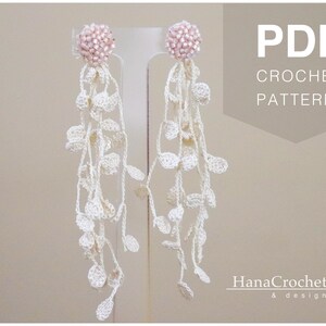 May include: PDF crochet pattern for a pair of white crocheted earrings with pink bead accents. The earrings are hanging from a display stand. The text "PDF CROCHET PATTERN" is displayed in the upper right corner of the image. The text "HanaCrochet & design" is displayed in the lower right corner of the image.