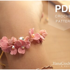 May include: A pink crochet bracelet with delicate flower designs and crystal accents. The bracelet is on a person's wrist. PDF CROCHET PATTERN.