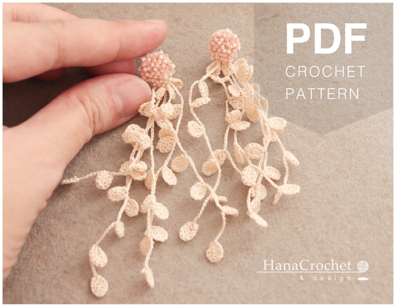 May include: A PDF crochet pattern for a pair of delicate, long, crocheted earrings with a pink beaded top. The earrings are made with white yarn and feature a cascading design of small, crocheted circles.