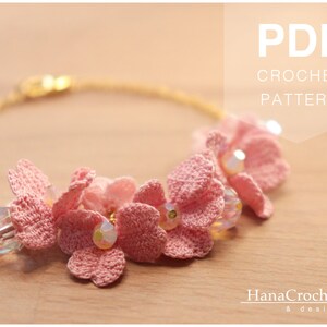 May include: A pink crochet bracelet with a gold chain and clear beads. The bracelet features a cluster of crocheted flowers. The text "PDF CROCHET PATTERN" is displayed at the top of the image. The text "HanaCrochet & design" is displayed at the bottom of the image.