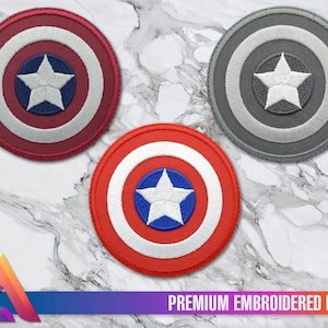 Könnte beinhalten: Drei gestickte Aufnäher mit dem ikonischen Captain America-Schild-Design. Die Aufnäher sind rot, weiß und blau, grau und weiß sowie schwarz, weiß und grau. Jeder Aufnäher zeigt einen weißen Stern in der Mitte.