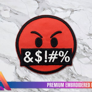 May include: Red embroidered patch with a cartoon face with angry eyebrows and a black censor bar over the mouth with the text "& $ ! # %" on it. The patch is on a white marble background.