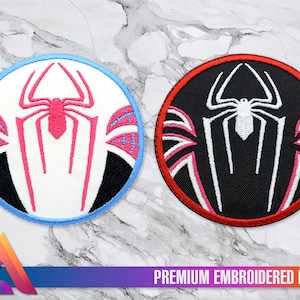 Op de afbeelding: Twee geborduurde patches met een gestileerd spinnenwebontwerp. De patch links heeft een witte achtergrond met een roze spin en een blauwe rand. De patch rechts heeft een zwarte achtergrond met een witte spin en een rode rand. Beide patches hebben de tekst "PREMIUM EMBROIDERED PATCH" onderaan.