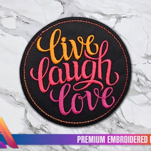 Könnte beinhalten: Ein runder, schwarzer gestickter Aufnäher mit den Worten "live laugh love" in orange, rosa und roter Schrift.