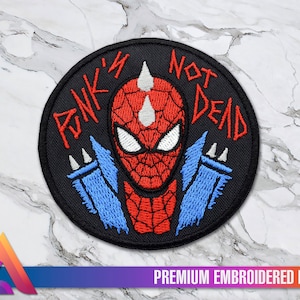 Può includere: Una toppa ricamata nera con un design di Spiderman rosso e blu. Il testo "Punk's Not Dead" è scritto in bianco attorno al bordo della toppa.