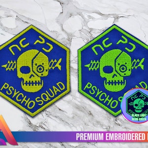 May include: A blue and green embroidered patch featuring a skull and crossbones design. The skull has a robotic eye and the text "NC PJ PSYCHO SQUAD" is written around the skull. The patch glows green under a black light.