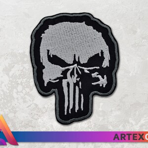 May include: A black and white embroidered patch of the Punisher skull. The skull is white with black outlines and details. The patch is made of fabric and has a stitched edge.