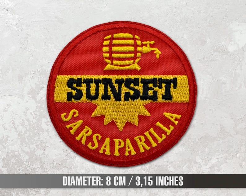 Op de afbeelding: Rode, gele en zwarte geborduurde patch met de tekst "Sunset Sarsaparilla" en een gestileerd beeld van een vat met een kraan.