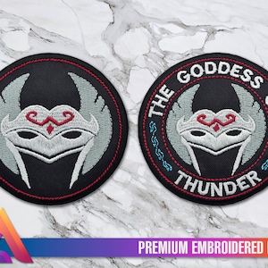 May include: Embroidered patch with a black background and red stitching. The patch features a white and gray mask with wings and the text "THE GODDESS OF THUNDER" in a red and blue circle.