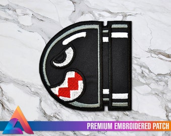 Puede incluir: Parche bordado en blanco y negro de un personaje de videojuego con una boca roja y blanca. El parche dice "PREMIUM EMBROIDERED PATCH" en la parte inferior.