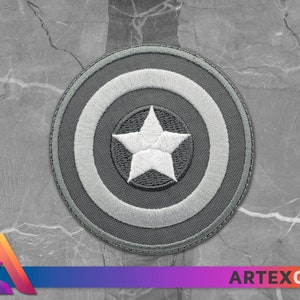 May include: A gray embroidered patch with a white star in the center, surrounded by a white circle and a gray outer circle.
