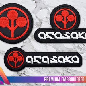 Pode incluir: Três patches bordados com o logotipo Arasaka. O logotipo é uma árvore vermelha estilizada com três folhas sobre um fundo preto. O texto "Arasaka" é bordado em branco sobre um fundo preto.