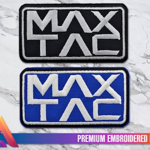 Op de afbeelding: Twee geborduurde patches met de tekst "MAX TAC" in witte letters. De bovenste patch heeft een zwarte achtergrond en de onderste patch heeft een blauwe achtergrond. Beide patches hebben een zwarte rand.
