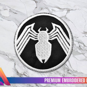 Peut inclure: Un patch brodé noir et blanc représentant le logo du symbiote Venom. Le logo est une araignée blanche sur fond noir avec une bordure circulaire blanche.