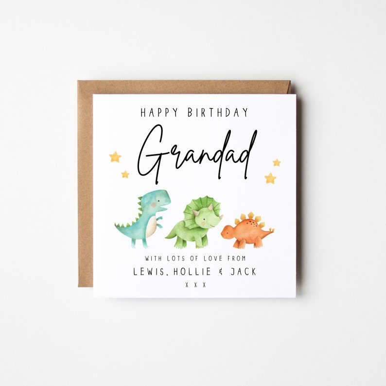 May include: Happy Birthday Grandad card with three cartoon dinosaurs, a blue, a green, and an orange dinosaur. The card has gold stars and the text "With lots of love from Lewis, Hollie & Jack xxx".